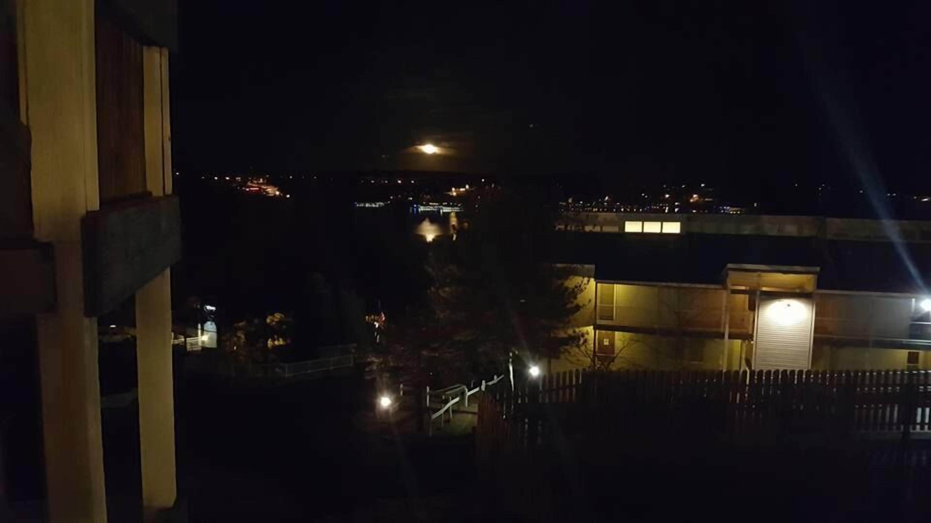 Vista nocturna de un edificio con una escalera iluminada y la luna de fondo.