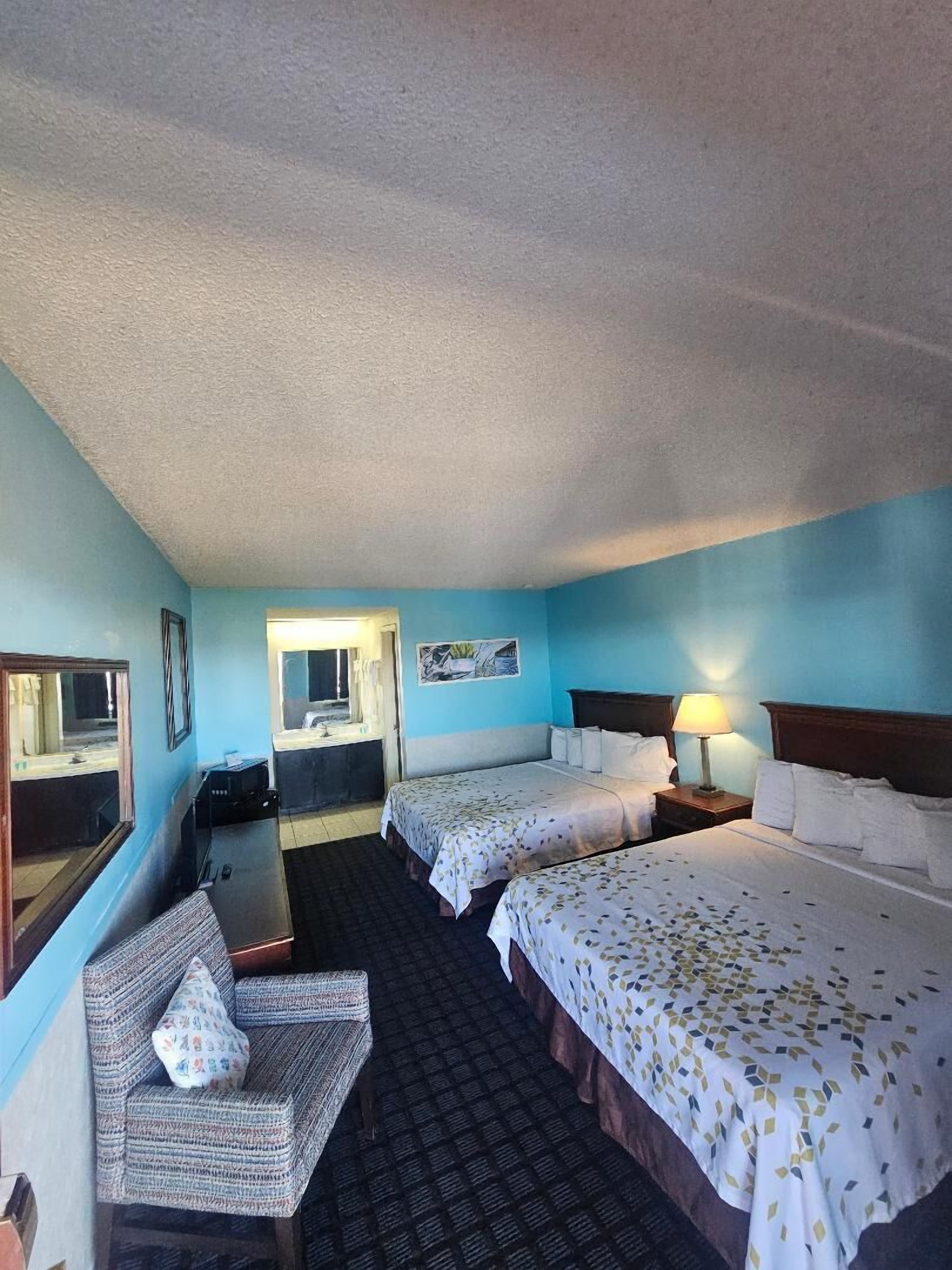Een hotelkamer met twee bedden, een stoel, een bureau en een spiegel.