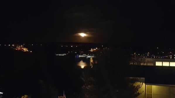 A nighttime view of a cityscape with a prominent full moon in the sky. - Hawk's Nest Lodge (Osage Beach)