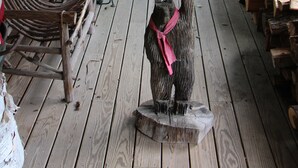 A wooden porch with a welcome sign, a rocking chair, and a pile of firewood. - Kiwassa Lake Bed & Breakfast (Saranac Lake)