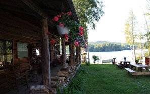 Un chalet rustique doté d’une véranda, de meubles en bois et de paniers de fleurs suspendus.