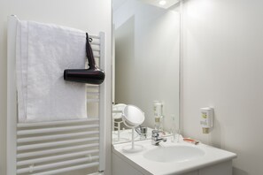 Een badkamer met een witte wastafel, spiegel, handdoekrek en een haardroger.