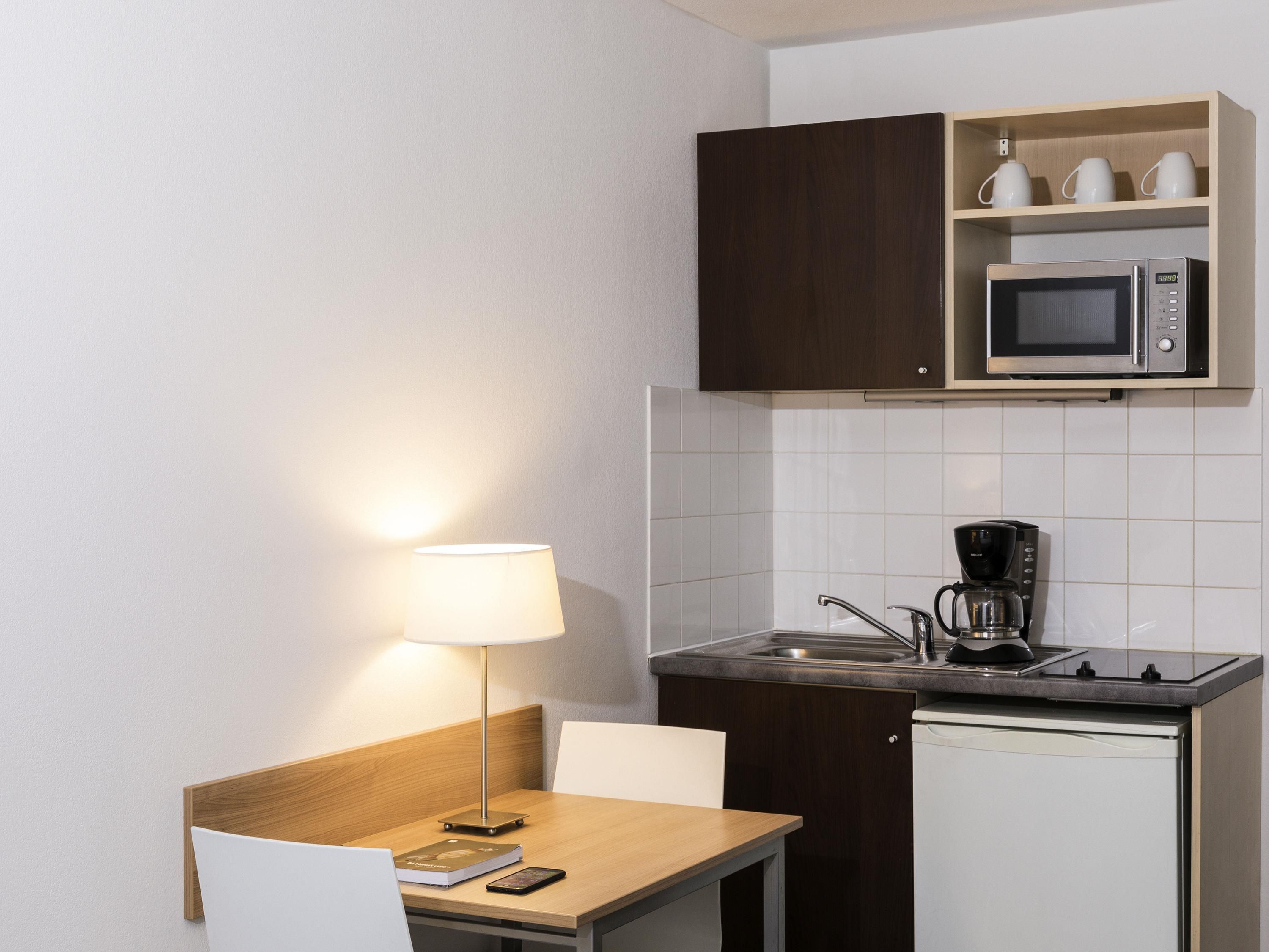 A compact kitchenette with a microwave, coffee maker, and a small sink.