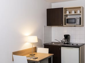 A compact kitchenette with a microwave, coffee maker, and a small sink. - Aparthotel Adagio Access Paris Clamart (Clamart)