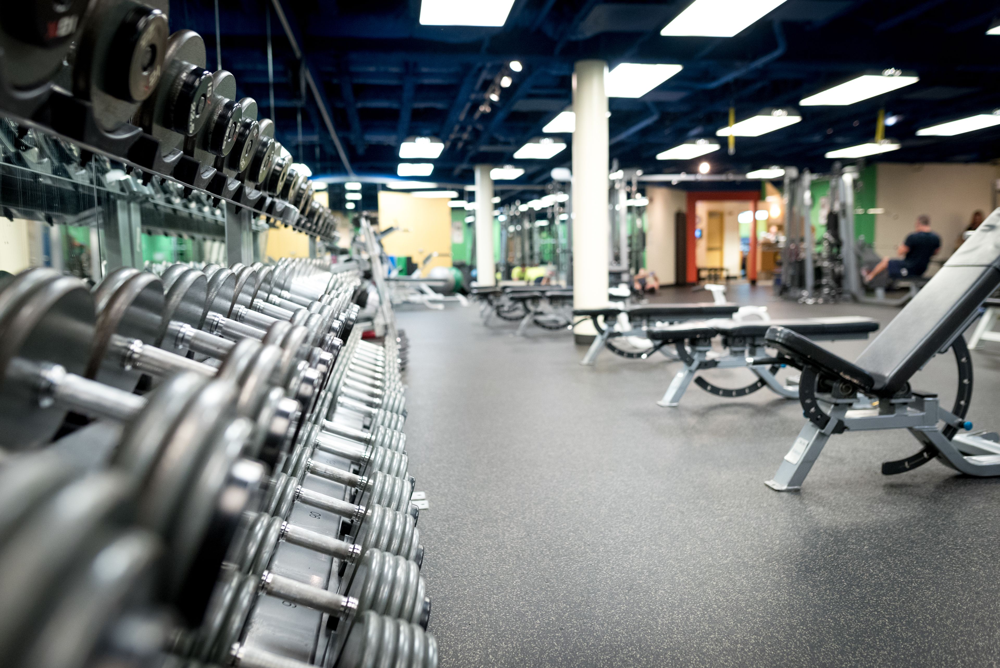 A gym with rows of dumbbells, benches, and various exercise equipment.