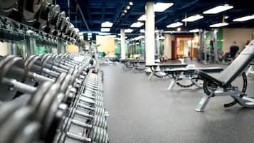A gym with rows of dumbbells, benches, and various exercise equipment.