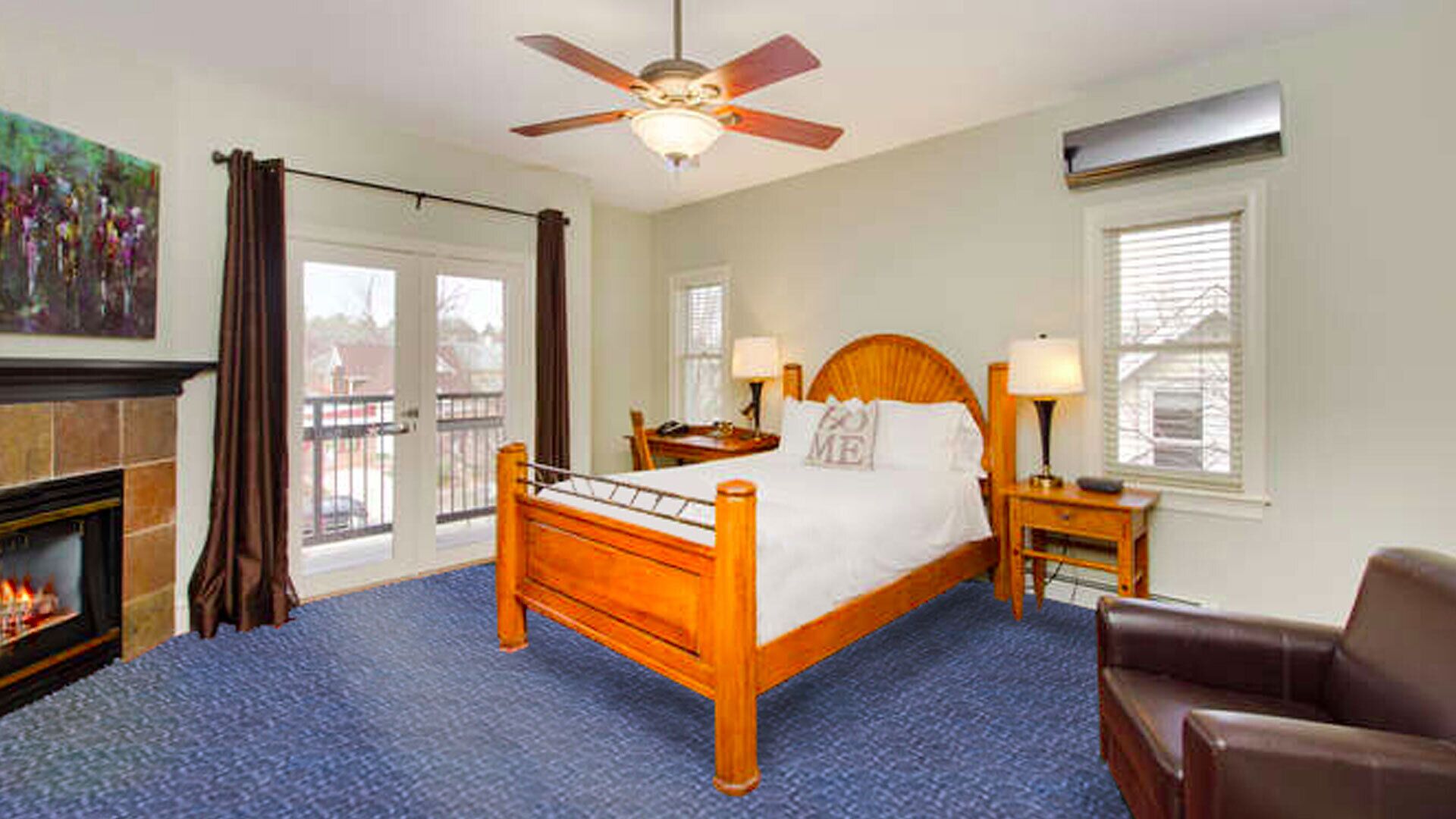 A hotel room with a wooden bed, a ceiling fan, a fireplace, and a view of the outside.