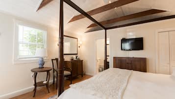 A bedroom with a four-poster bed, a television mounted on the wall, and a wooden cabinet.