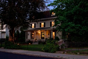 A two-story house with a porch, a front door, and a small garden area. - Marshall Slocum Inn (Newport)