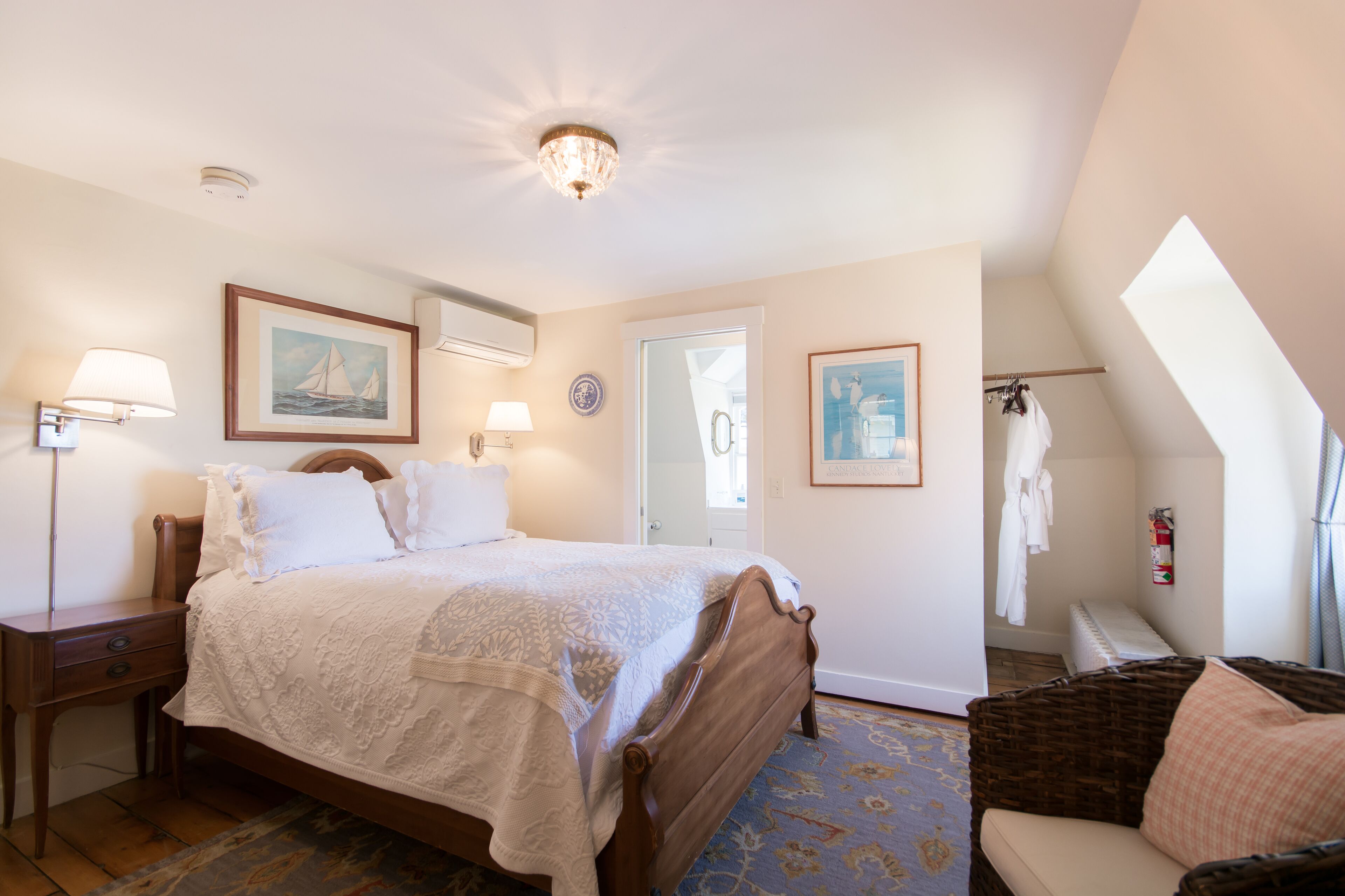 A bedroom with a bed, bedside lamps, a nightstand, a chair, a door, and a window.