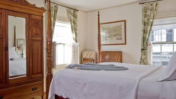 A bedroom with a four-poster bed, a wooden wardrobe, and a large mirror.