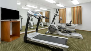 A hotel room with a treadmill, elliptical, and stationary bike, a TV, and a mirror. - Super 8 by Wyndham Cloverdale Wine Country (Cloverdale)