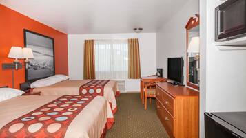 A hotel room with two beds, a desk, a TV, and a large window with curtains.