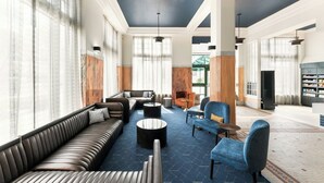 A spacious lobby with a leather sofa, blue armchairs, and a marble accent wall.