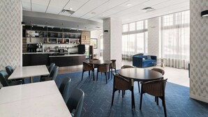 A modern hotel lobby with a bar area, seating arrangements, and large windows providing natural light.