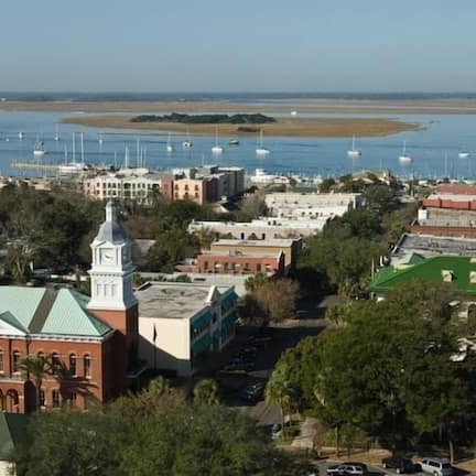 A coastal town with a prominent church, a marina with boats, and a mix of residential and commercial buildings.