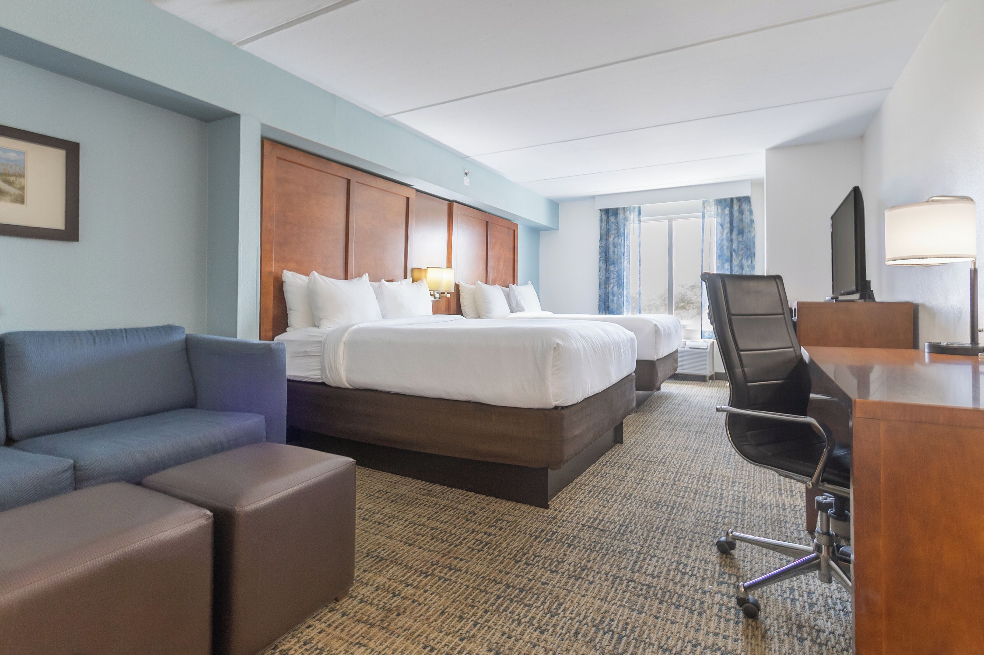 A hotel room with a large bed, a desk, a chair, a couch, and a television.