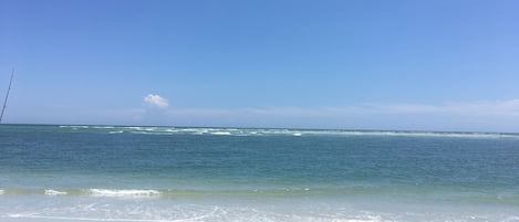 A beach with a fishing rod on the sand and the ocean in the background.