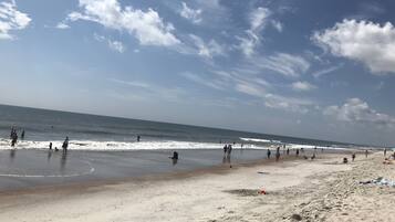 A beach with people walking and playing in the water.