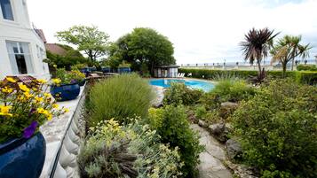 A pool surrounded by lush greenery and potted plants.