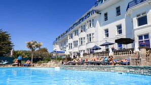 A hotel with a pool area, outdoor seating, and a clear blue sky. - Marsham Court Hotel (Bournemouth)