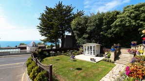 A well-maintained garden with a stone pathway leading to a gazebo, surrounded by lush greenery and colorful flowers. - Marsham Court Hotel (Bournemouth)