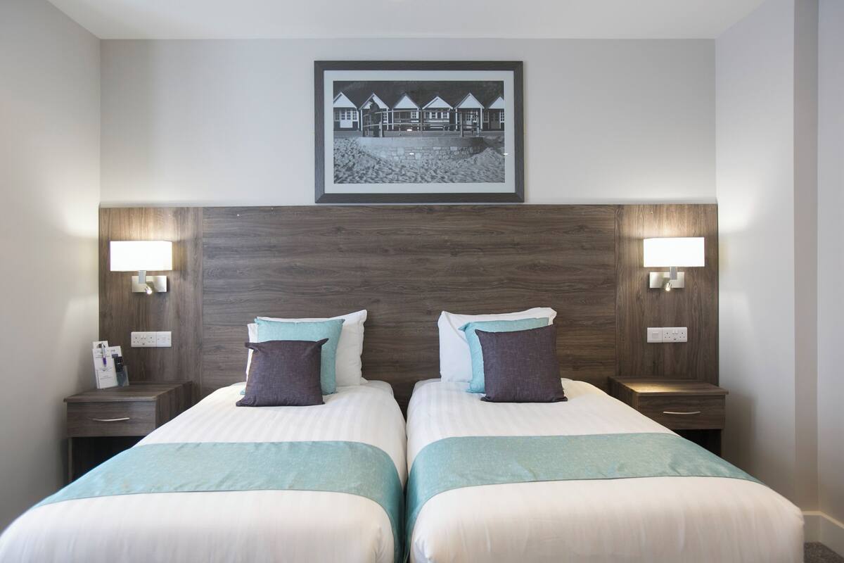 A hotel room with two beds, a framed picture on the wall, and bedside lamps.