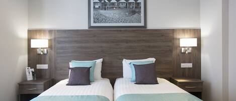 A hotel room with two beds, a framed picture on the wall, and bedside lamps.