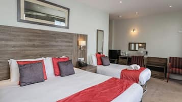 Une chambre d’hôtel avec deux lits, un bureau, une chaise et un miroir.