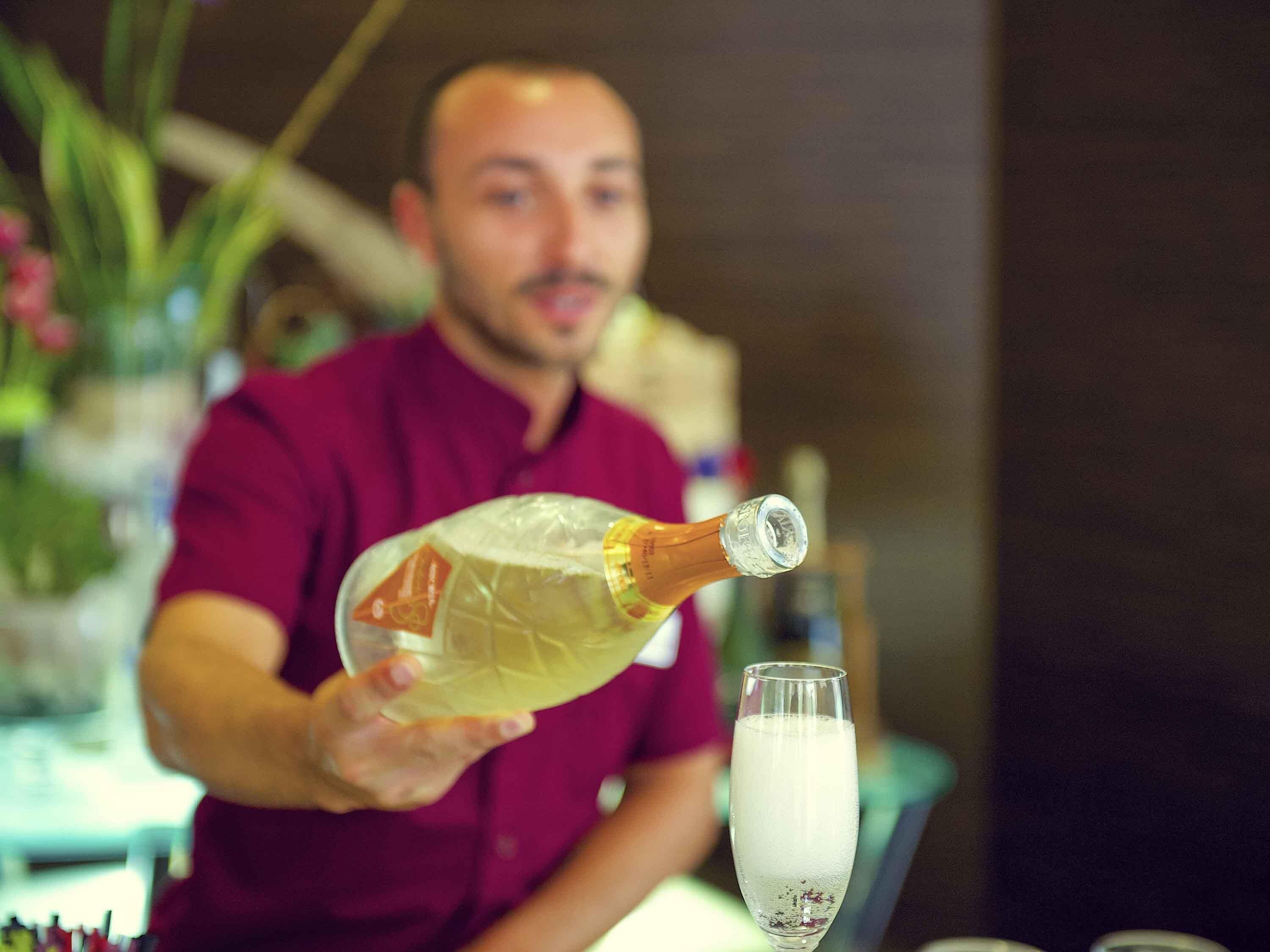 Une personne qui verse une boisson d’une bouteille dans un verre.