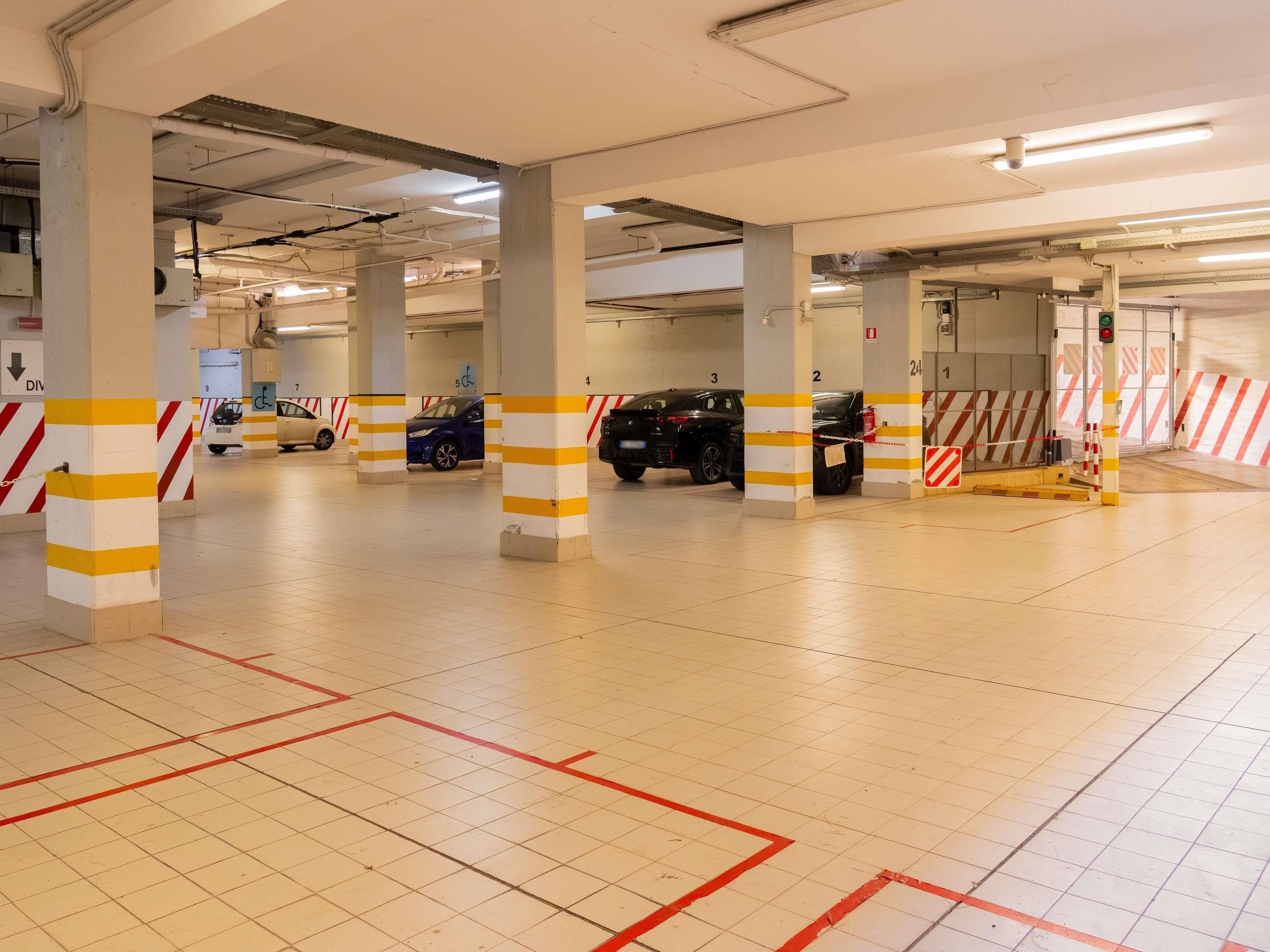 Eine mehrgeschossige Parkgarage mit deutlich gekennzeichneten Stellplätzen, barrierefreien Parkbereichen und einem Feuerlöscher.