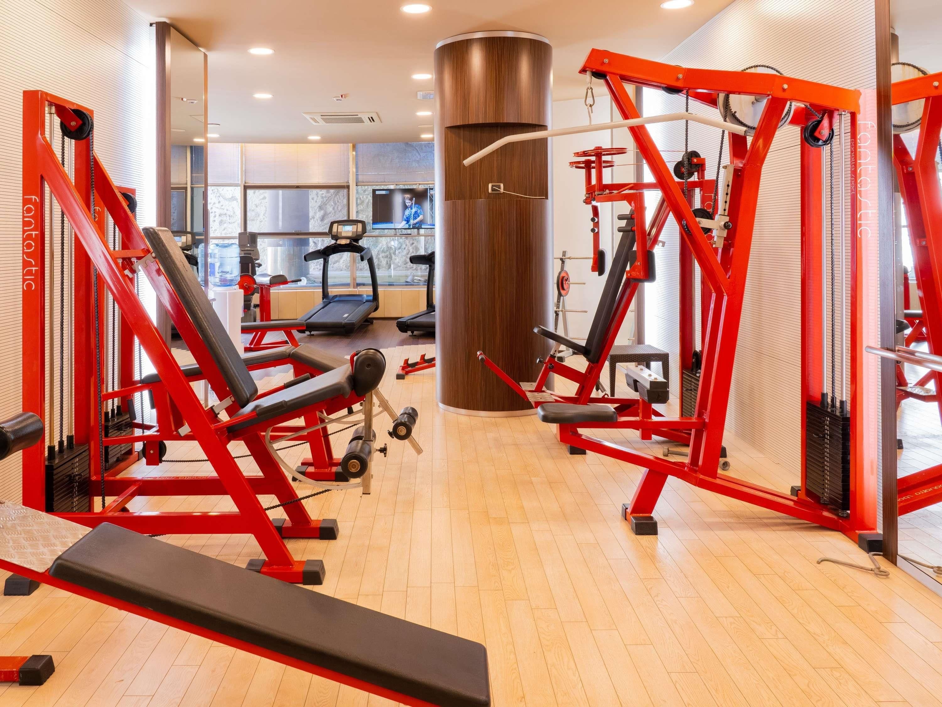 A gym with exercise equipment, treadmills, and a large pillar.