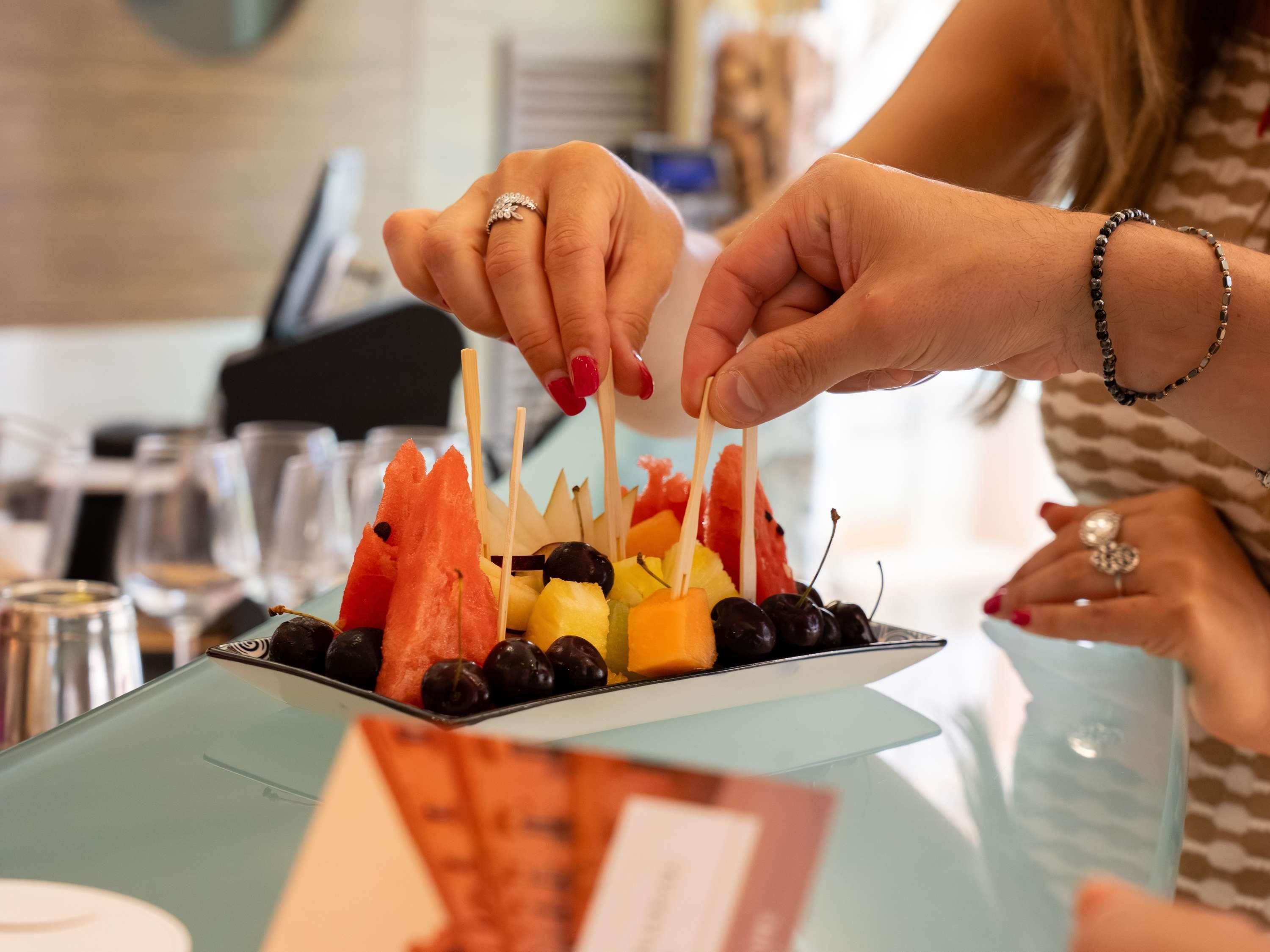 Una persona sosteniendo un palillo con brochetas de frutas.