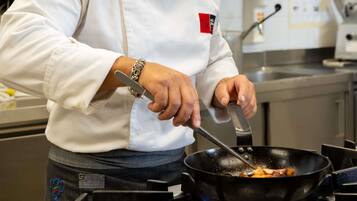 Une personne qui cuisine dans une cuisine équipée d’une cuisinière et d’une poêle.