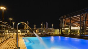 A nighttime pool area with a clear view of the pool, lounge chairs, and umbrellas. - Mercure Siracusa Prometeo (Syracuse)