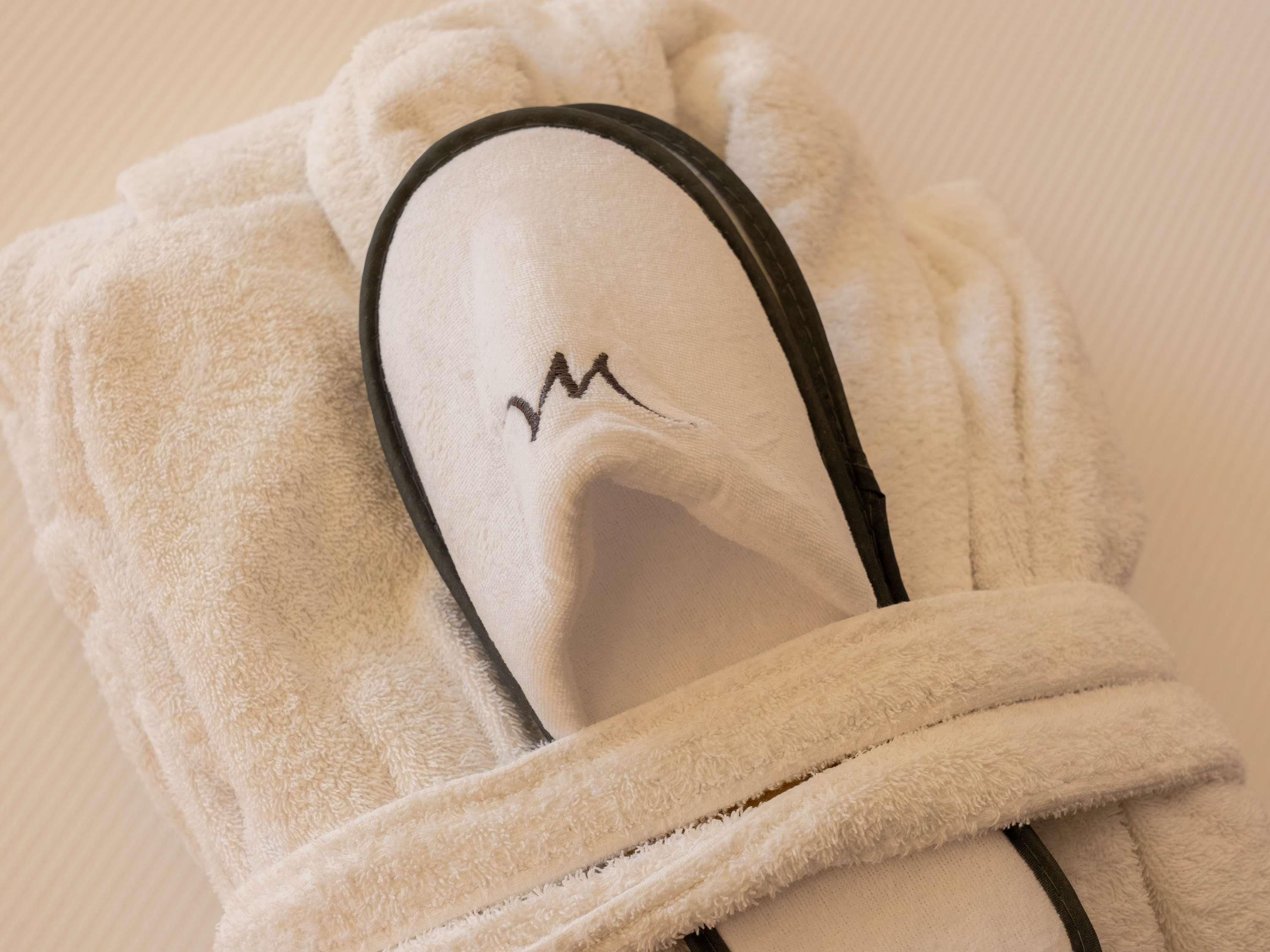 A white towel with a black border and a black embroidered letter 'M' on it.