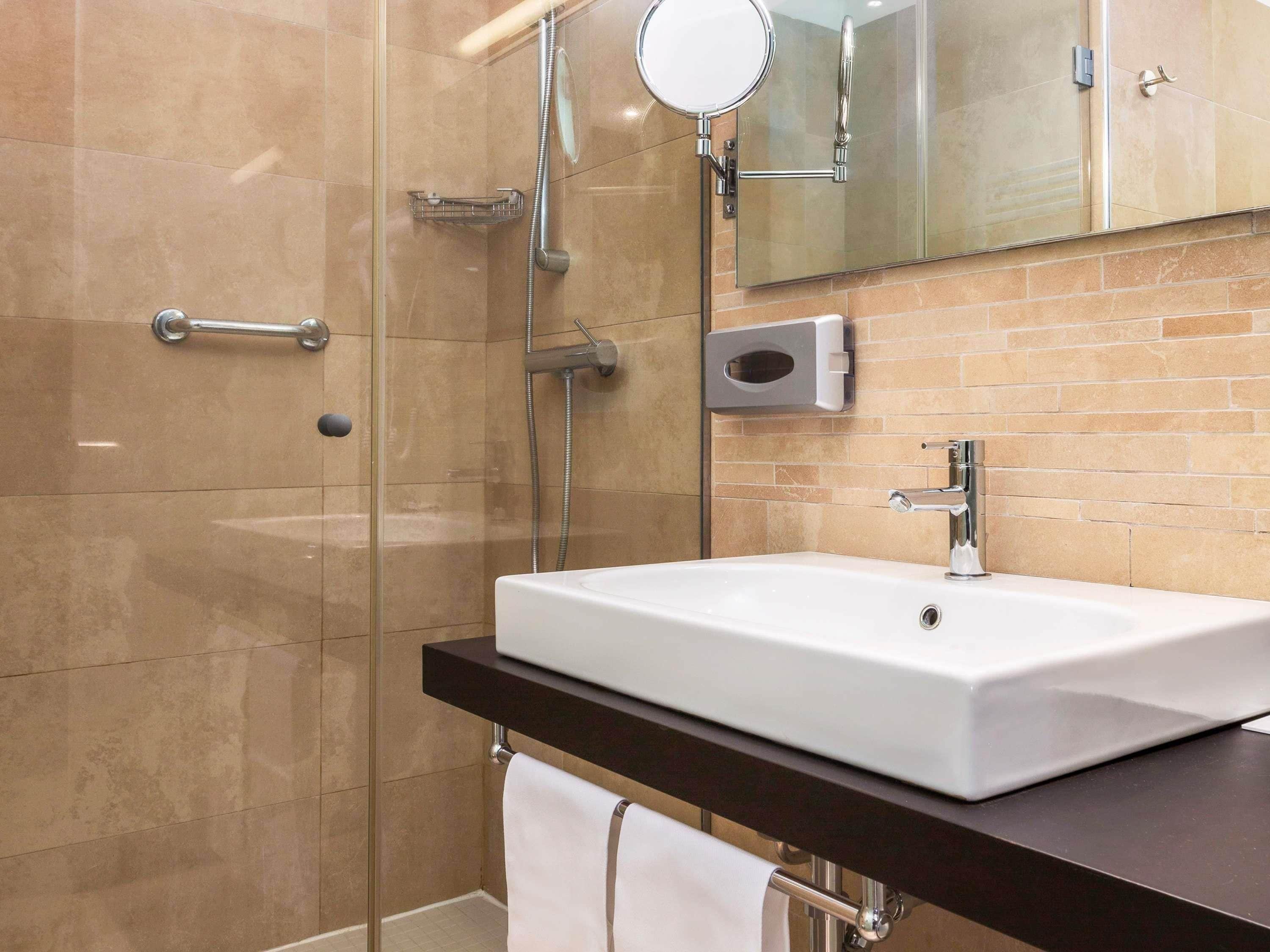 Un baño moderno con cabina de ducha de vidrio, un lavabo blanco y un espejo.