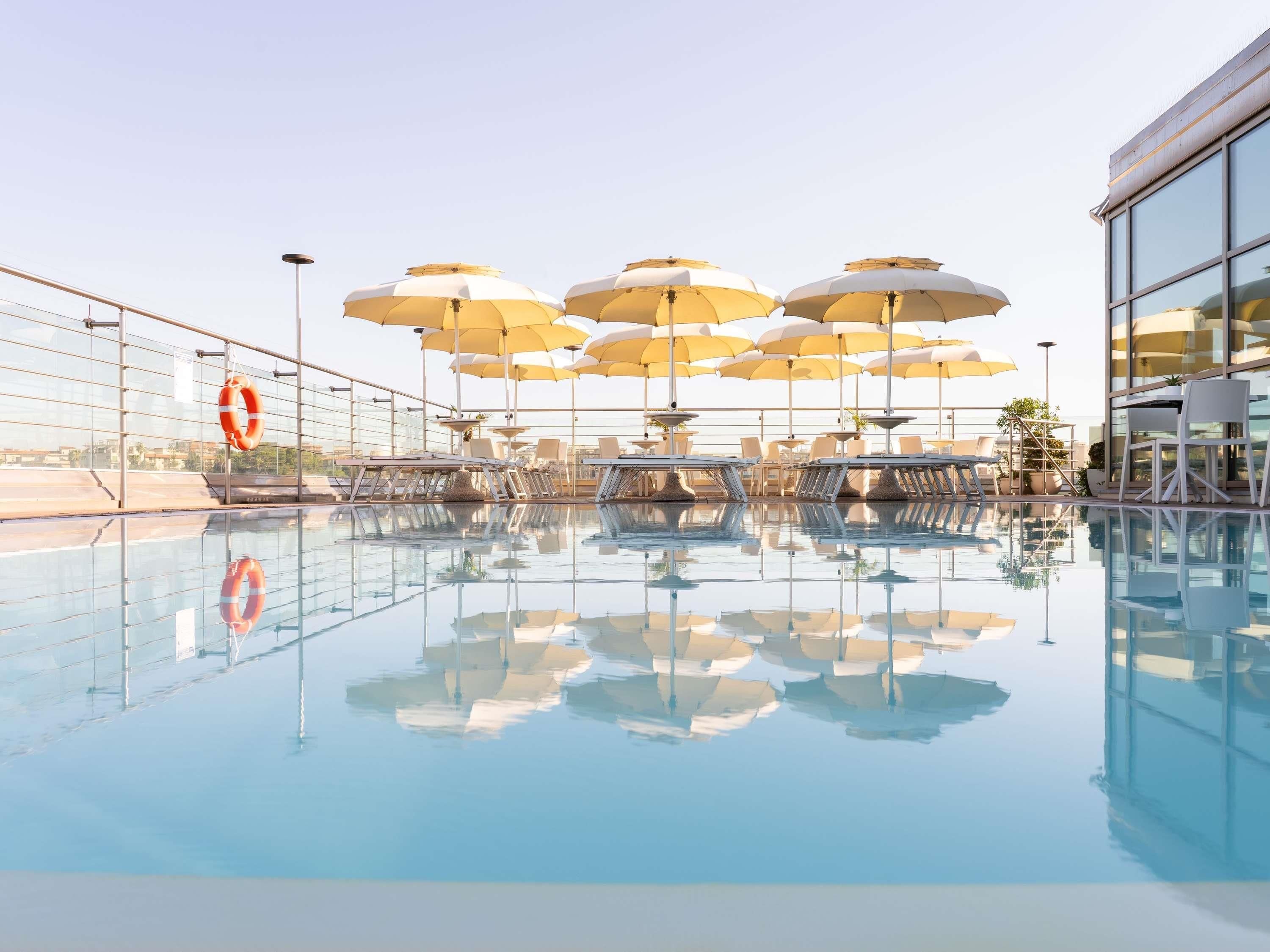 Ein Poolbereich mit mehreren Sonnenschirmen, Liegestühlen und einem Rettungsring.