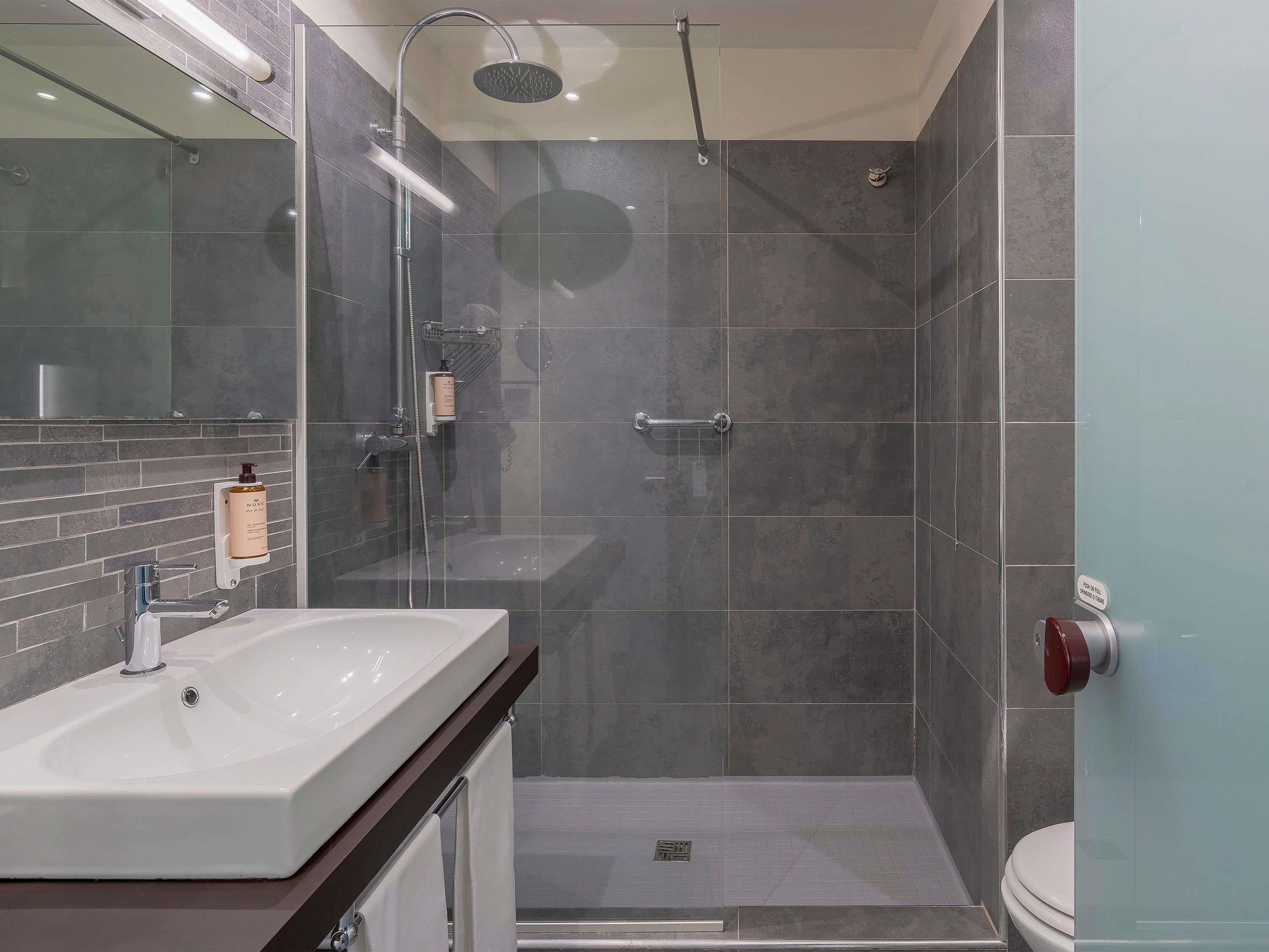 A modern bathroom with a shower, toilet, and sink.