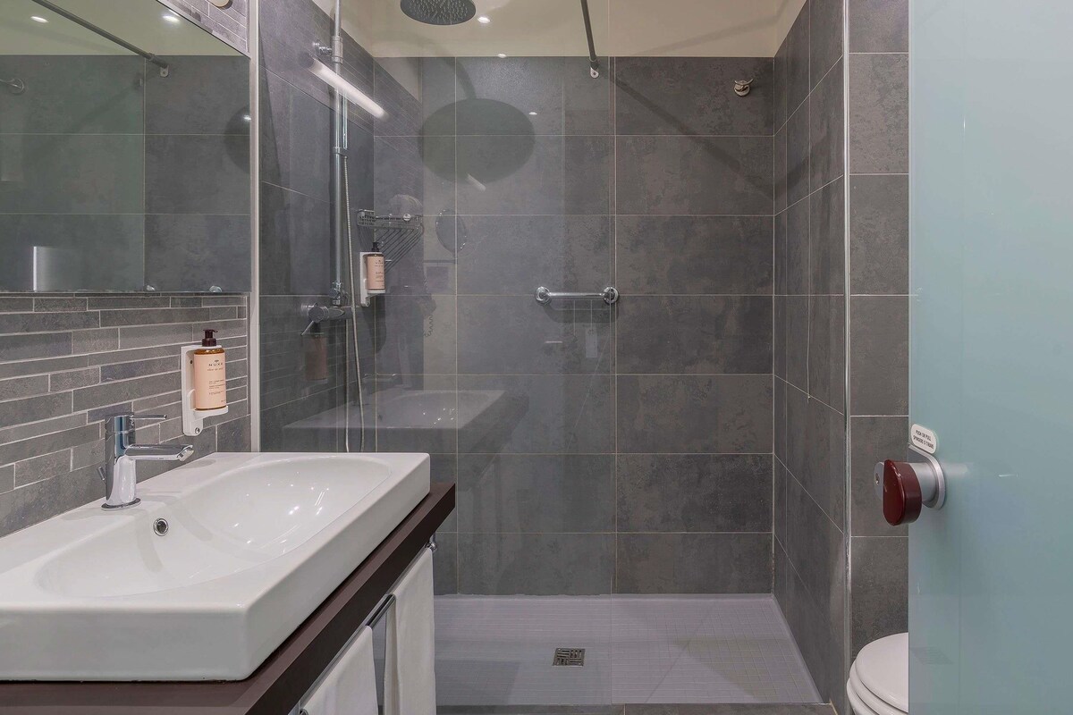 A modern bathroom with a shower, toilet, and sink.
