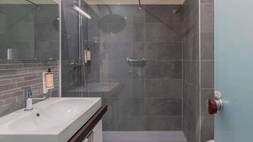 A modern bathroom with a shower, toilet, and sink.