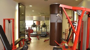 A gym with exercise equipment, a large mirror, and a wooden floor. - Mercure Siracusa Prometeo (Syracuse)