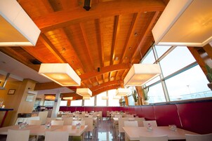 A spacious restaurant with high wooden ceilings and large windows.