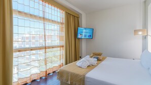 A hotel room with a bed, a TV mounted on the wall, and a window with curtains. - Mercure Siracusa Prometeo (Syracuse)