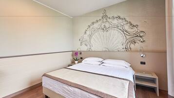 A bedroom with a large bed, a nightstand with a lamp, and a decorative wall headboard.