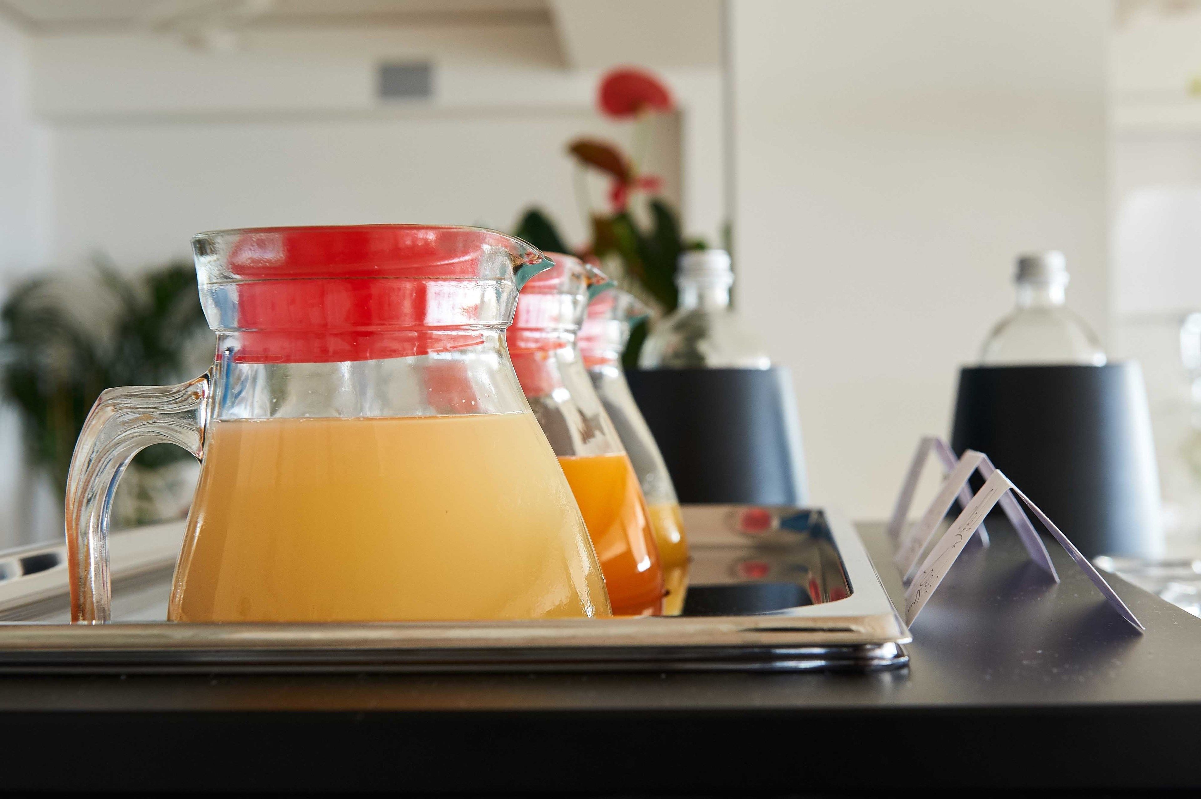 Una bandeja con jarras de jugo de naranja y un recipiente negro.