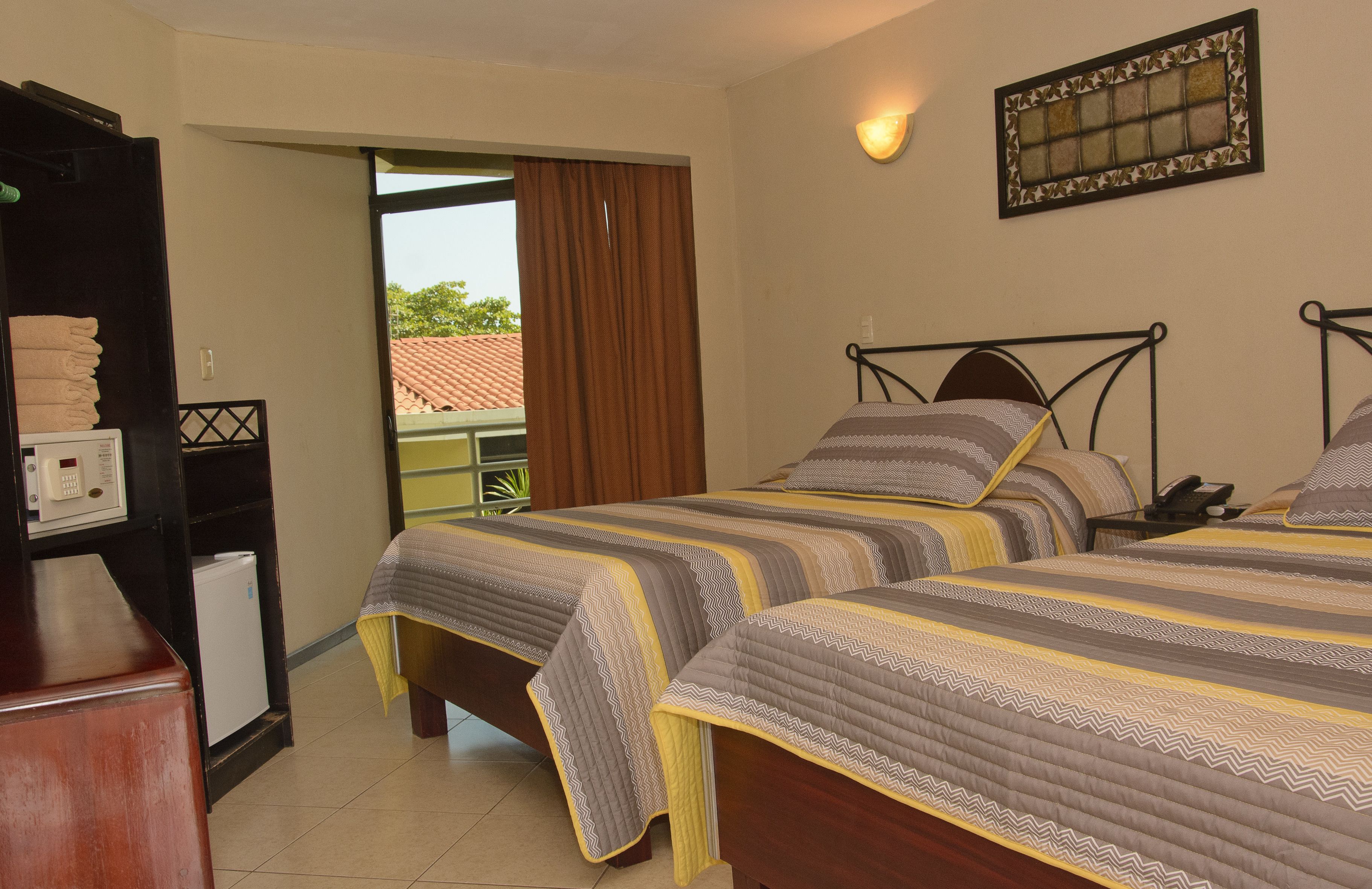 A hotel room with two beds, a desk with a telephone, and a small refrigerator.