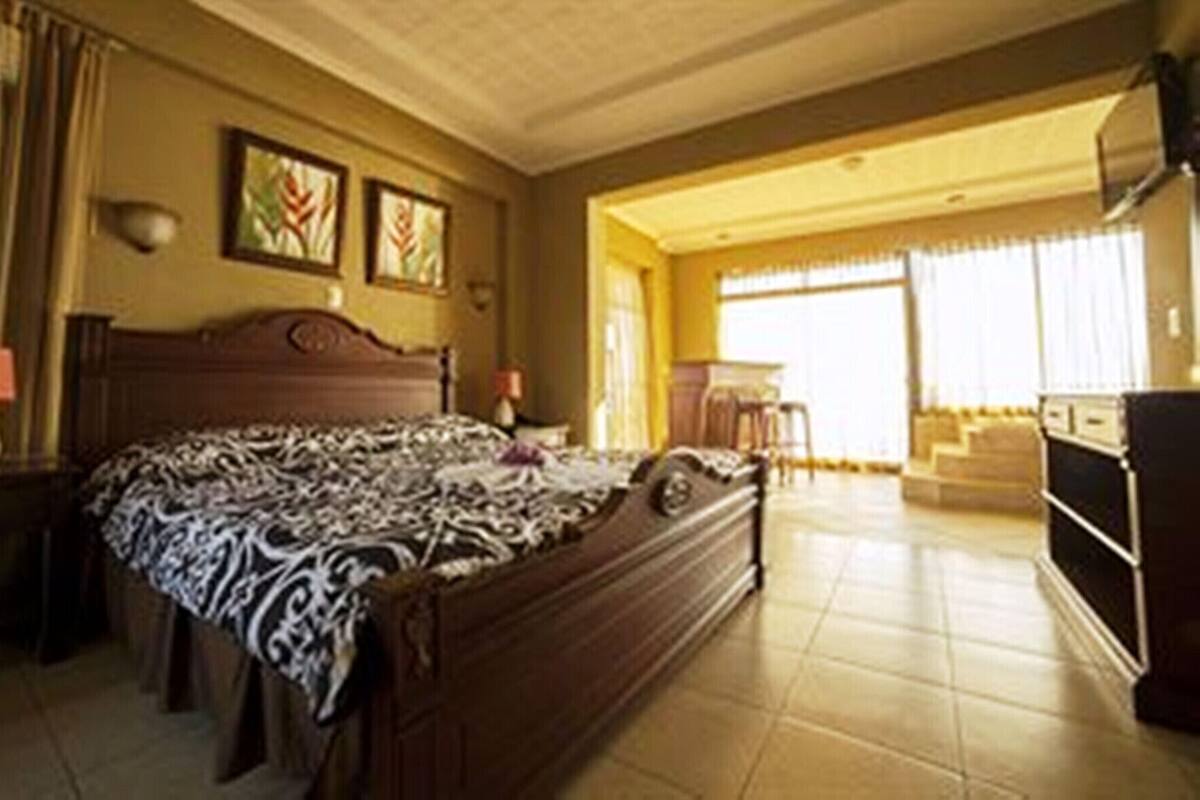 A bedroom with a large bed, a desk, and a television.