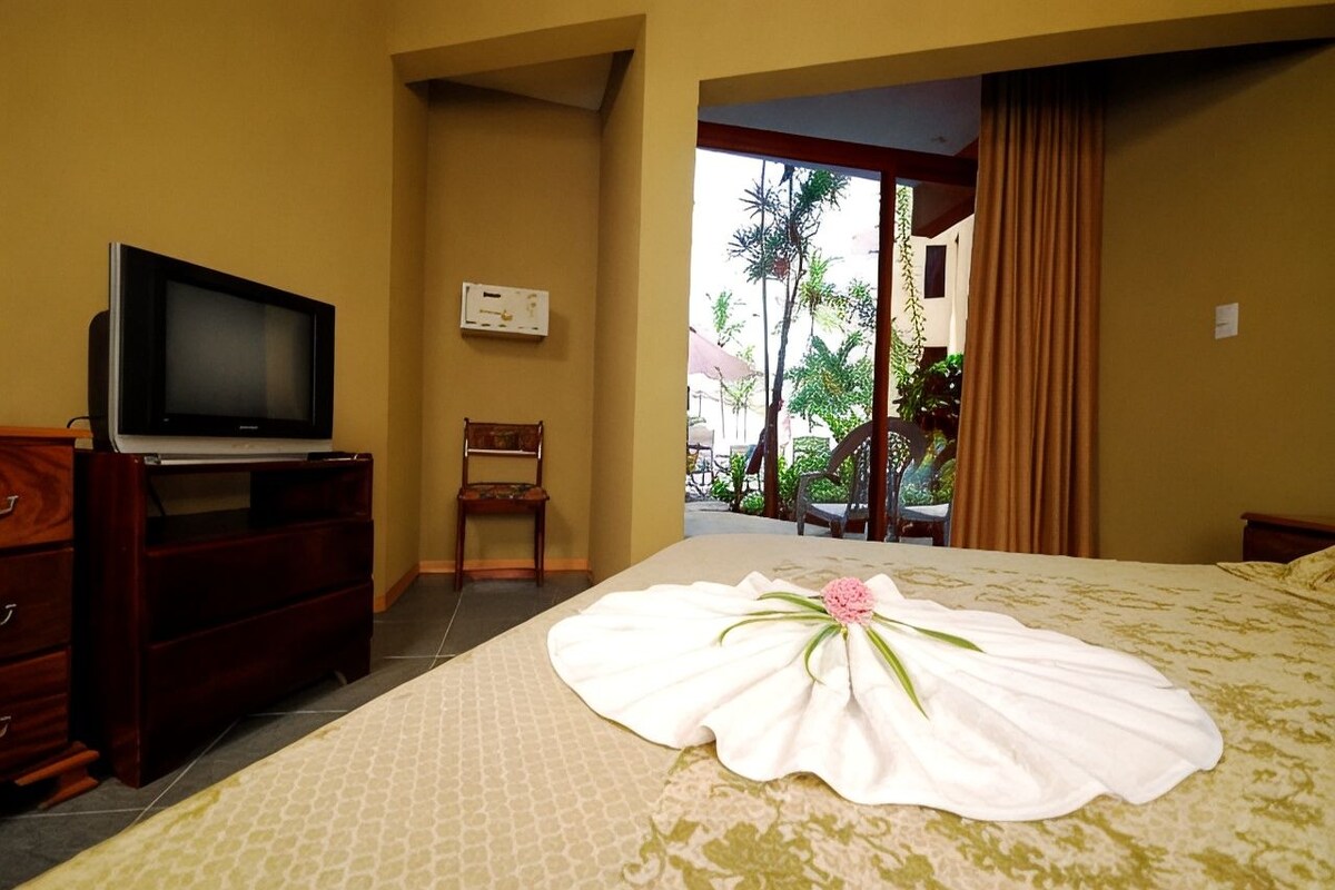 A hotel room with a bed, a television, a desk, and a chair.