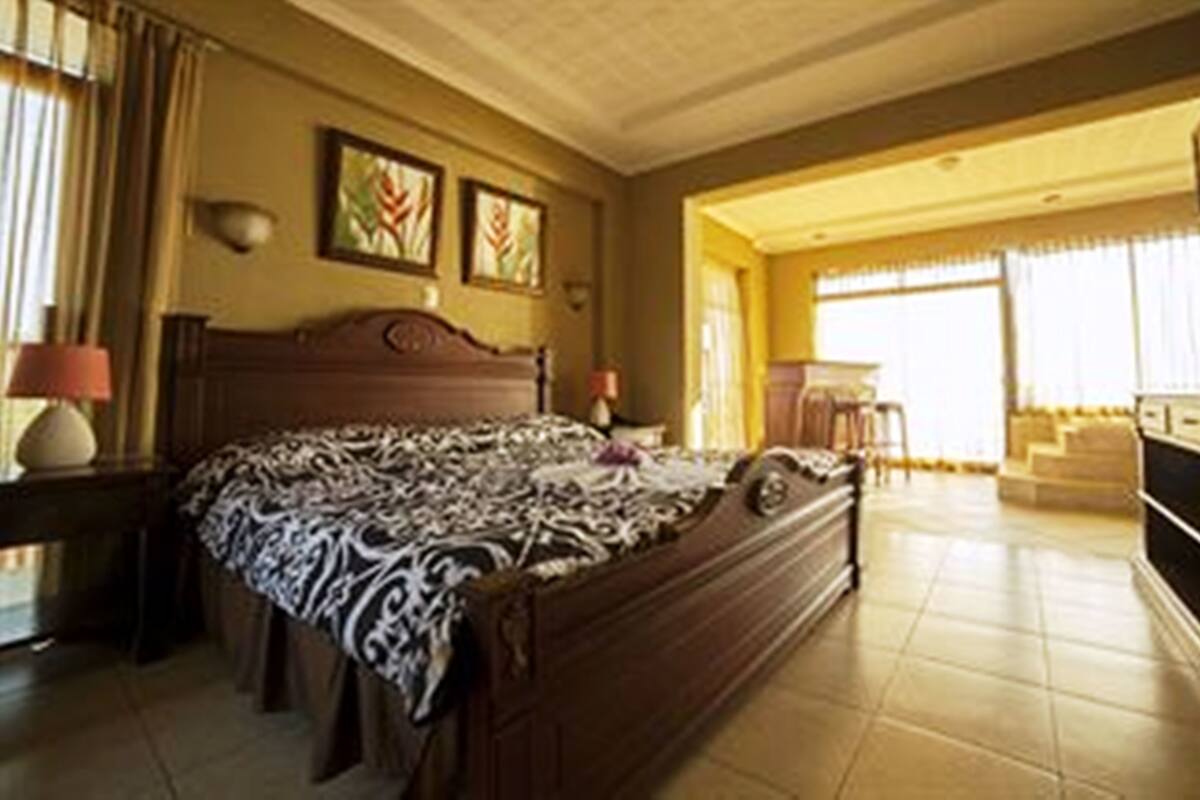 A spacious bedroom with a large bed, a desk, and a television.